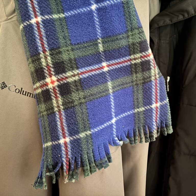 A fleece scarf bearing the Nova Scotia Tartan, which is a plaid with a blue background, and stripes of green, gold, white and red.