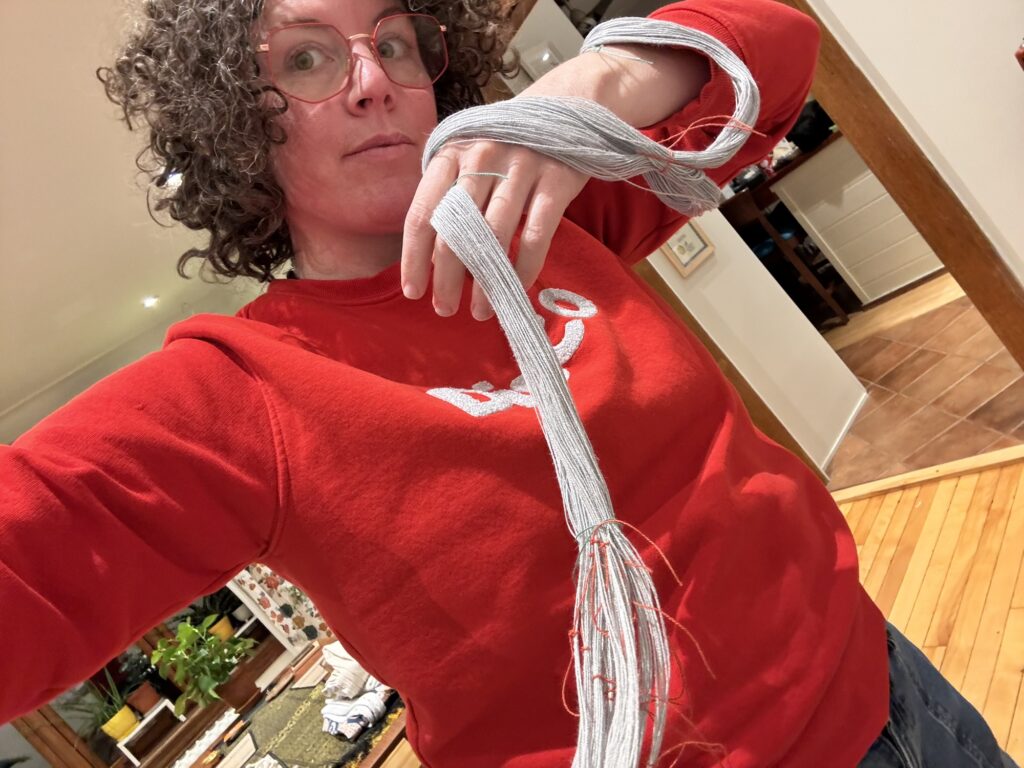 A selfie of me in my red DISCO sweatshirt, holding my warp.